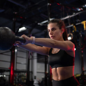 sweaty-sportswoman-exercising-with-kettlebell-5KFA73H